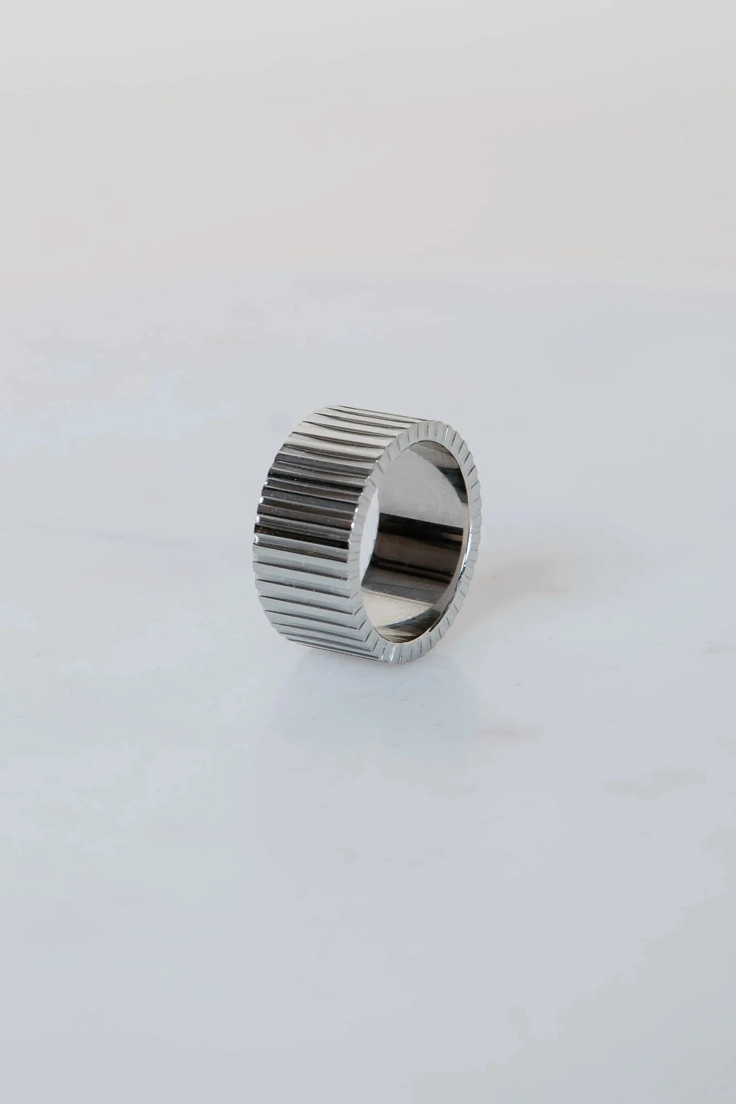 Silver ring with a ribbed design on a white background