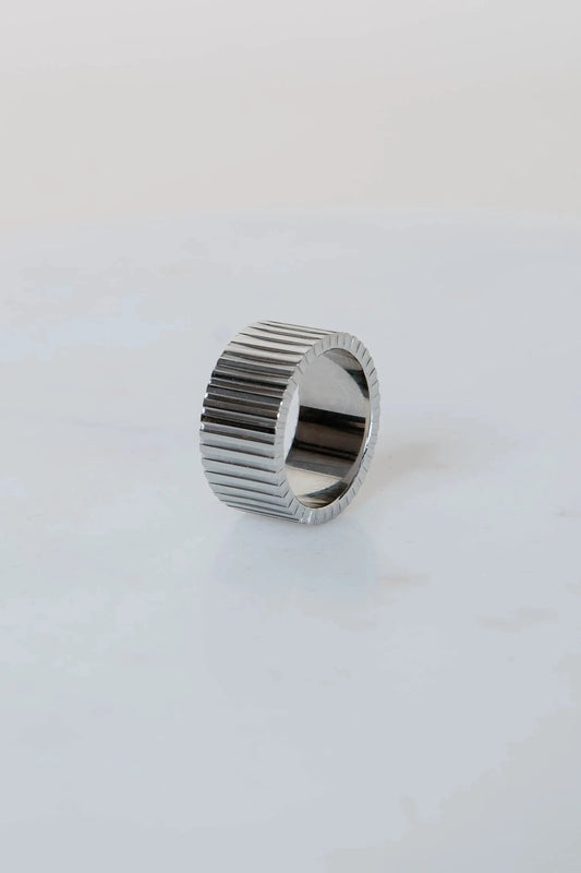 Silver ring with a ribbed design on a white background
