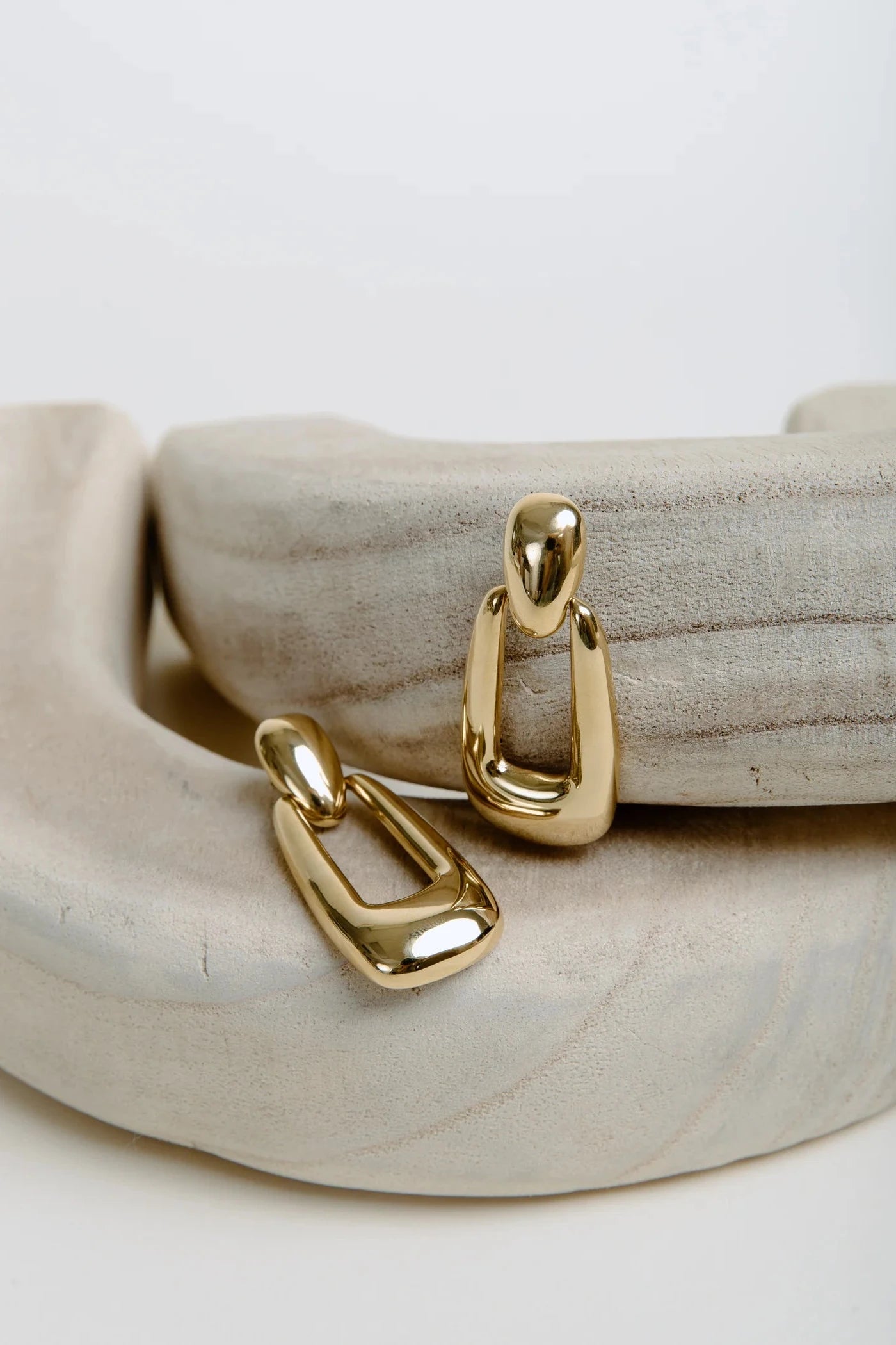 Gold hoop earrings on a textured beige surface