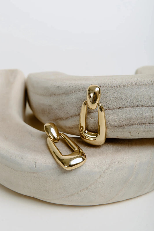 Gold hoop earrings on a textured beige surface