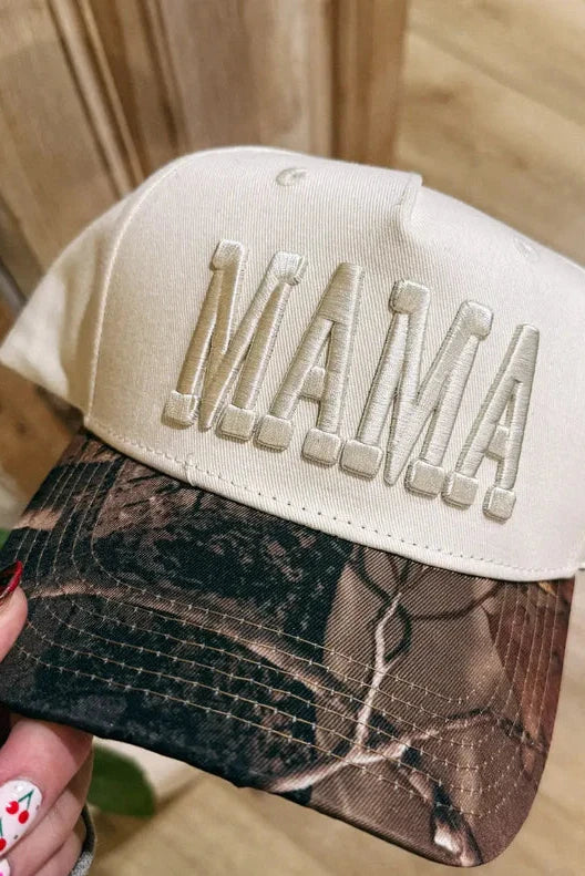 Cap with 'MAMA' text held by a person against a wooden background
