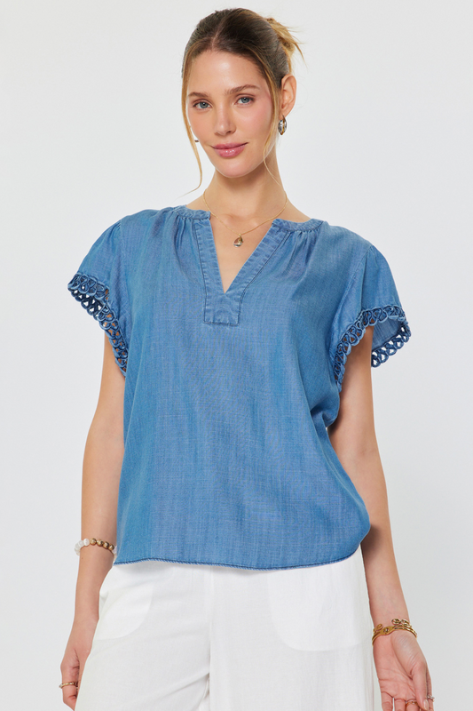 Woman wearing a blue denim top with lace trim on a white background