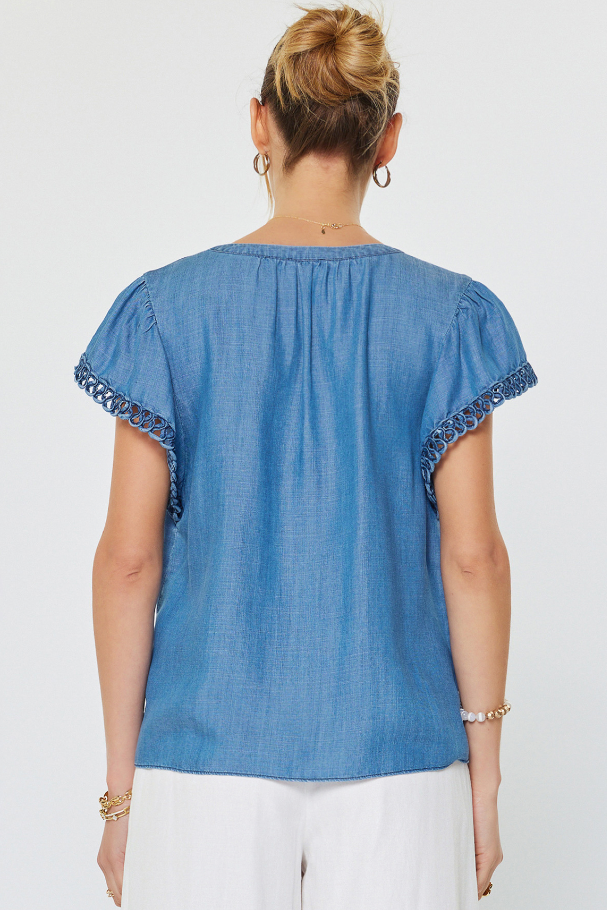 Woman wearing a blue top with decorative sleeves on a white background