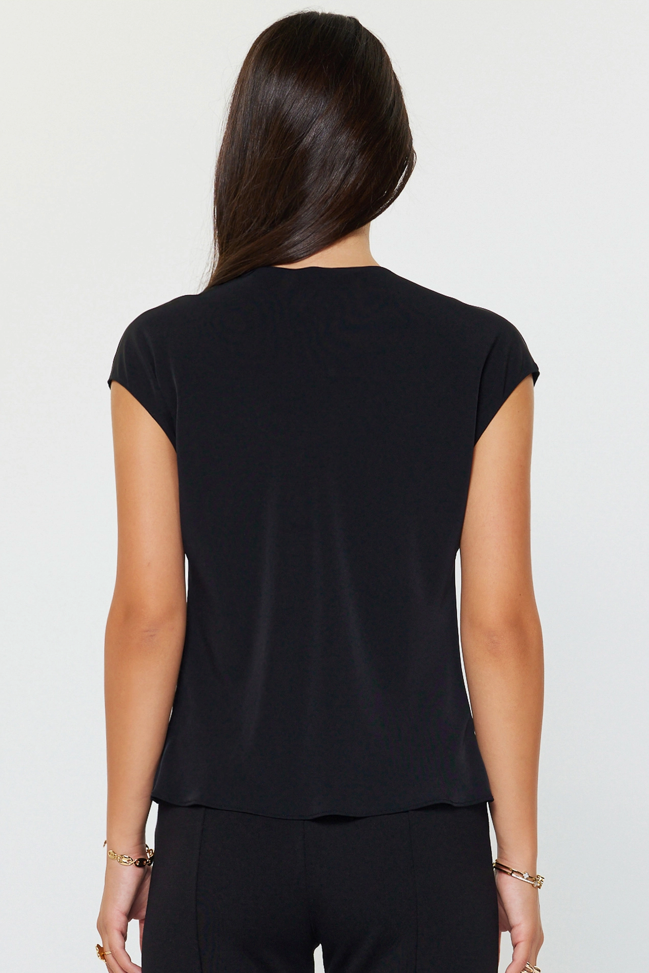 Person wearing a black cap-sleeve top on a white background
