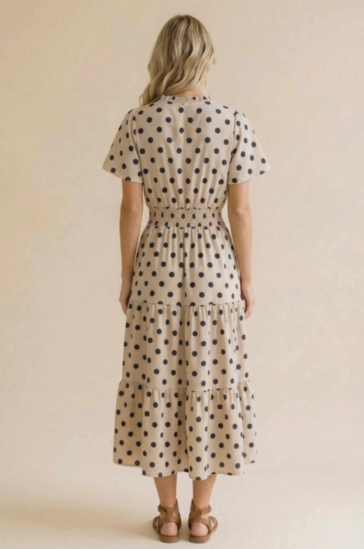 Woman wearing a polka dot dress against a beige background