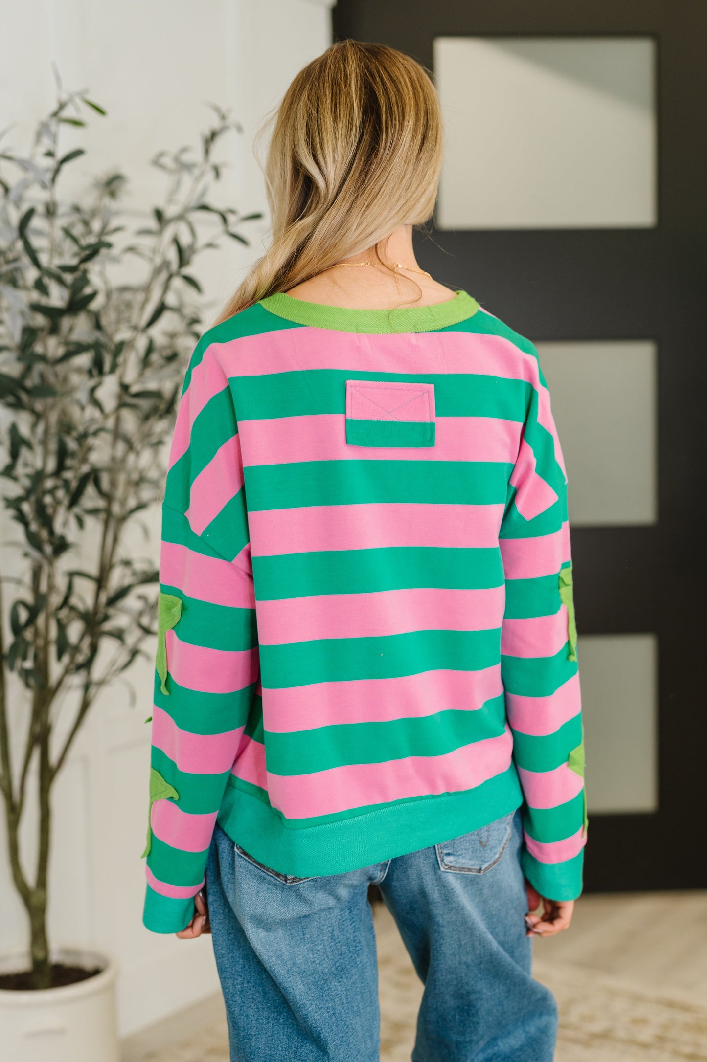 Person wearing a pink and green striped sweater in an indoor setting