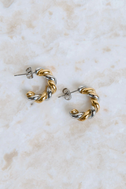 Pair of gold and silver hoop earrings on a marble surface