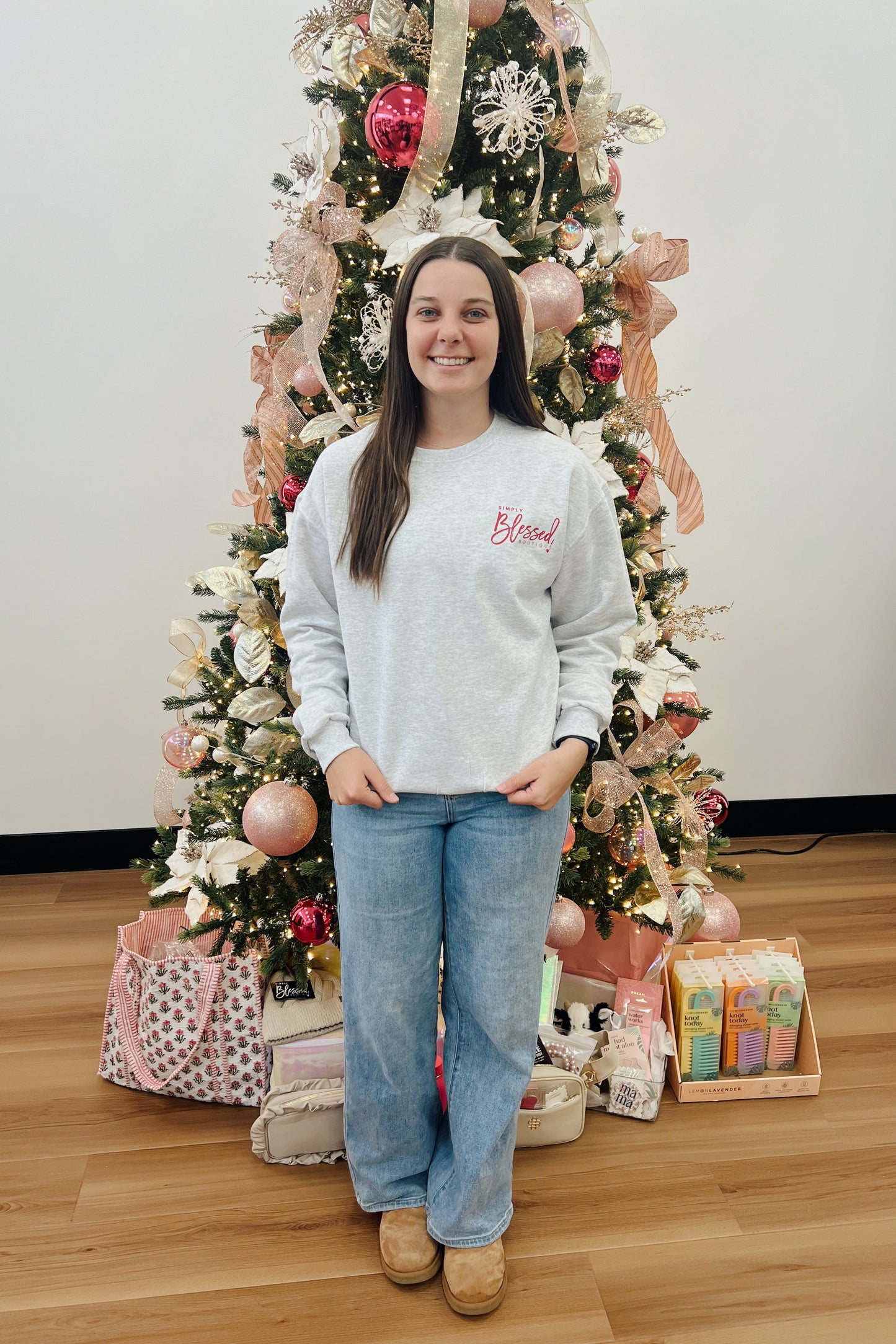 Person standing in front of a decorated Christmas tree with presents underneath.