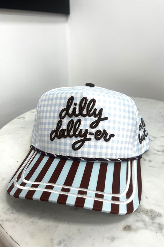 Checkered cap with 'dilly dally-er' text on a marble surface