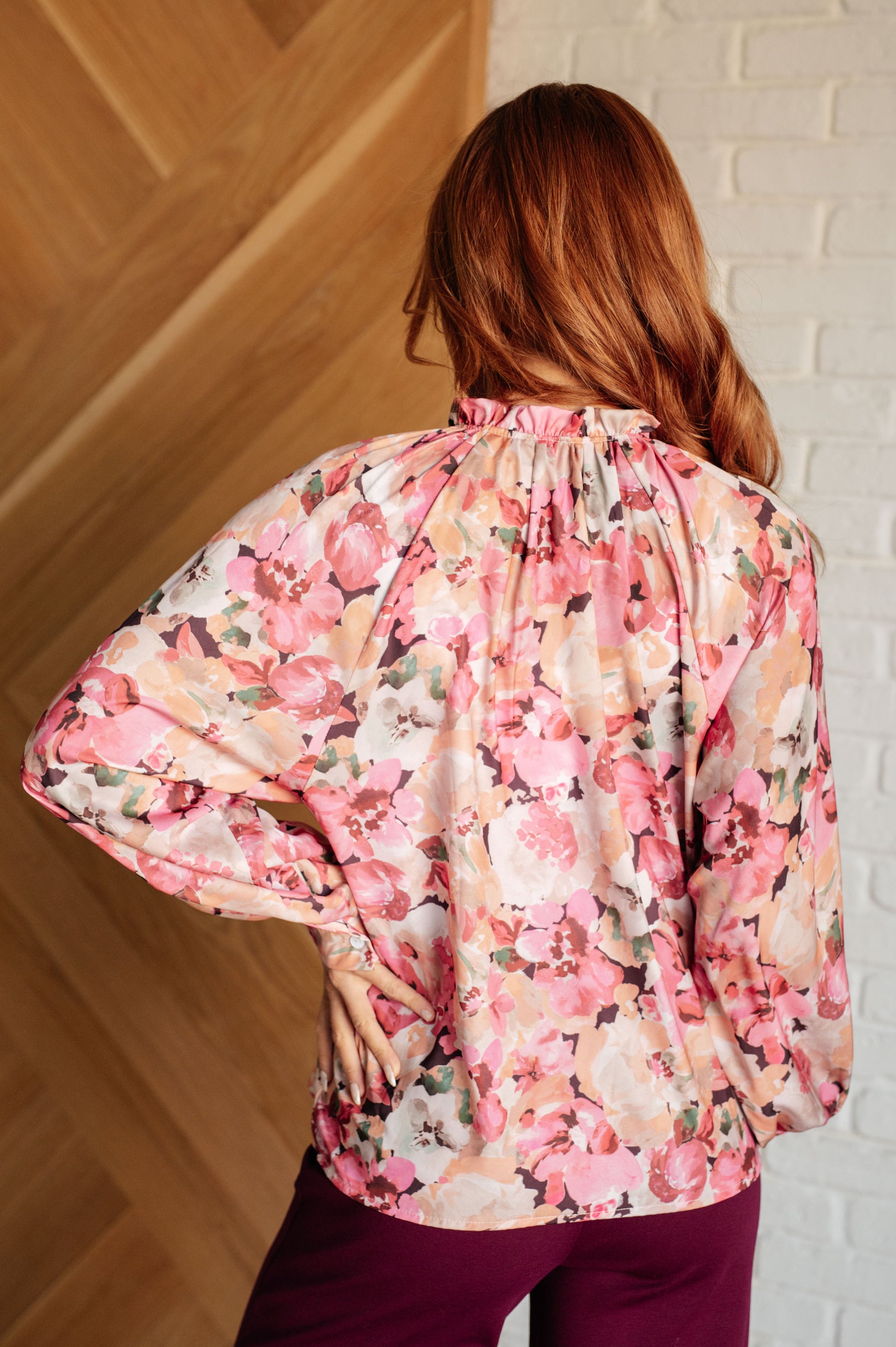 Woman wearing a floral blouse with a white brick wall background