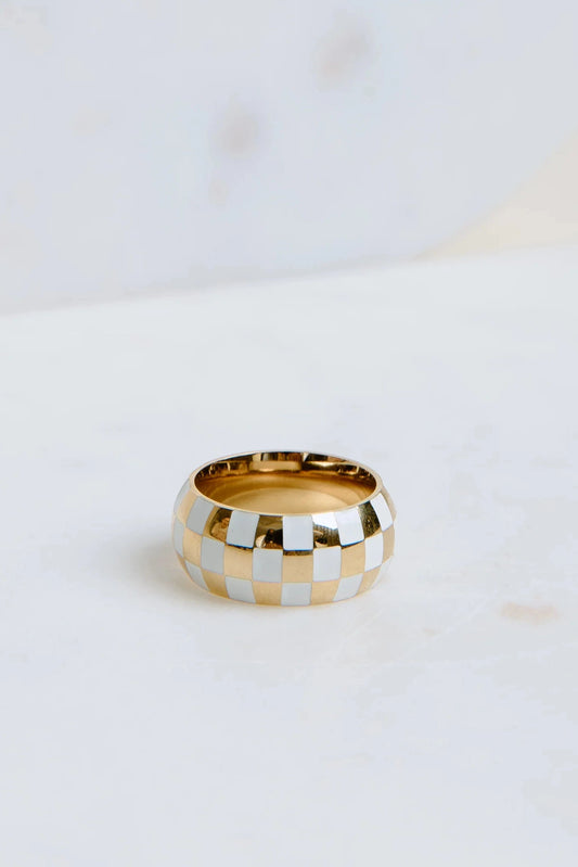 Gold and silver checkered ring on a white surface