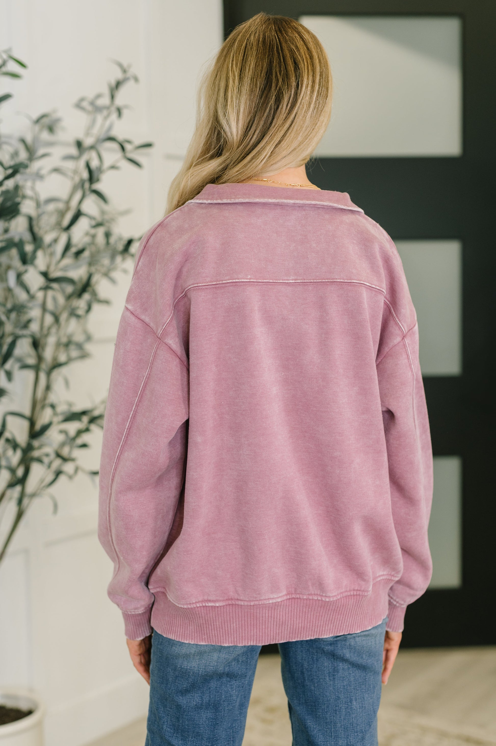 Person wearing a pink jacket and blue jeans in an indoor setting