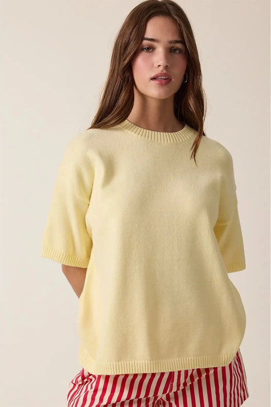 Woman wearing a light yellow sweater with a plain background