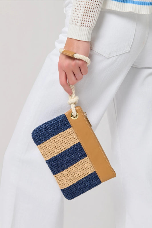 Hand holding a striped clutch bag with blue and brown colors against a plain background