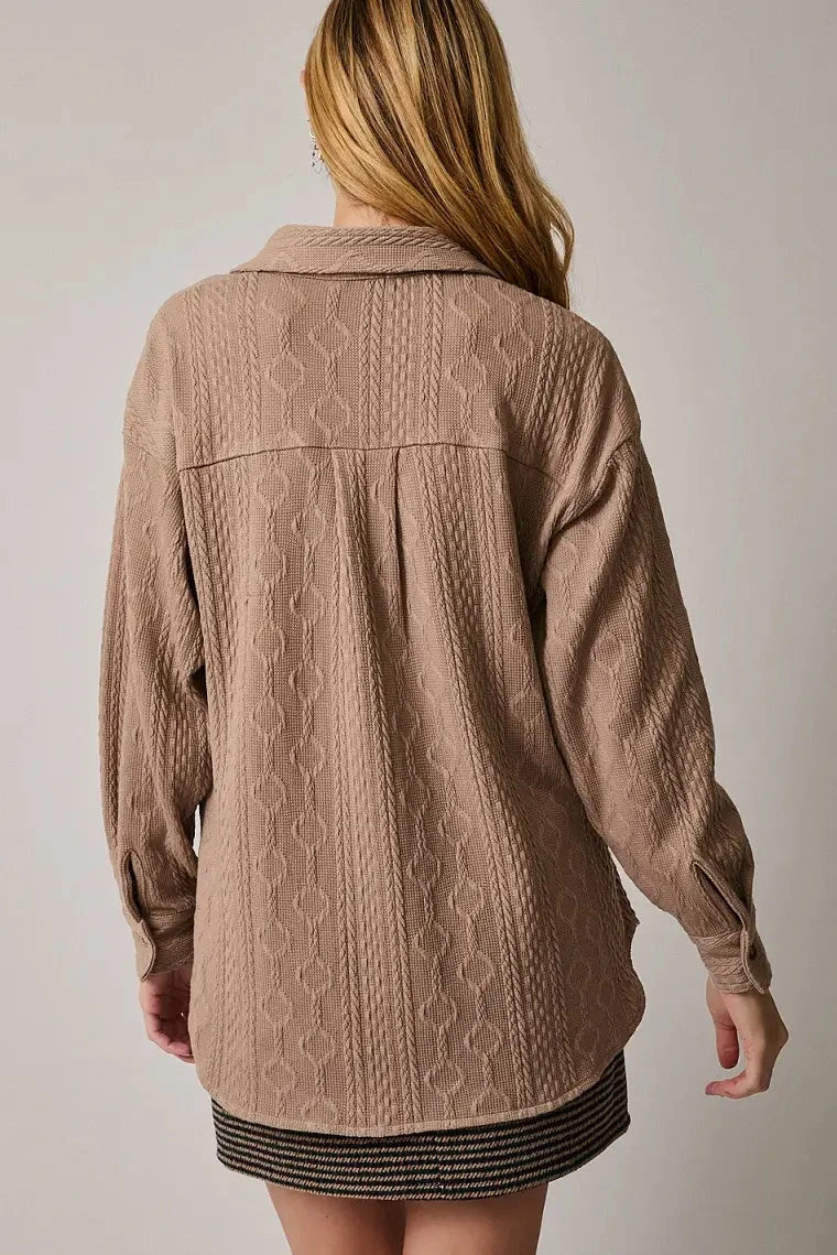 Person wearing a beige textured jacket against a plain background