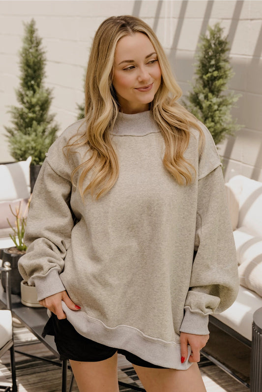 Woman wearing a gray oversized sweatshirt in an outdoor setting