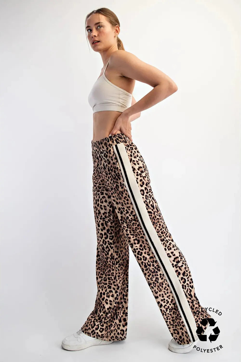 Woman wearing leopard print pants with white stripes on a white background