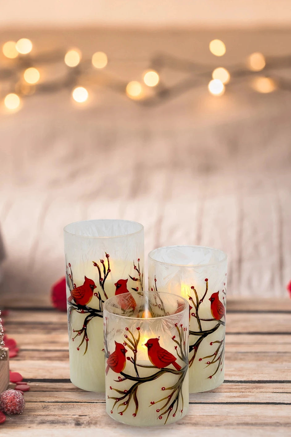 Decorative candles with cardinal designs on a wooden surface with festive decorations.