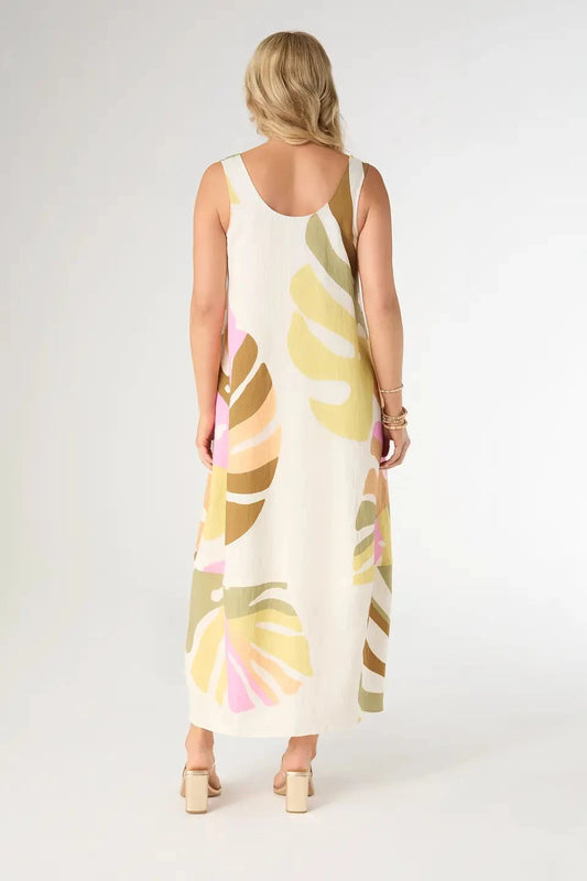 Woman wearing a sleeveless dress with colorful leaf pattern on a plain background