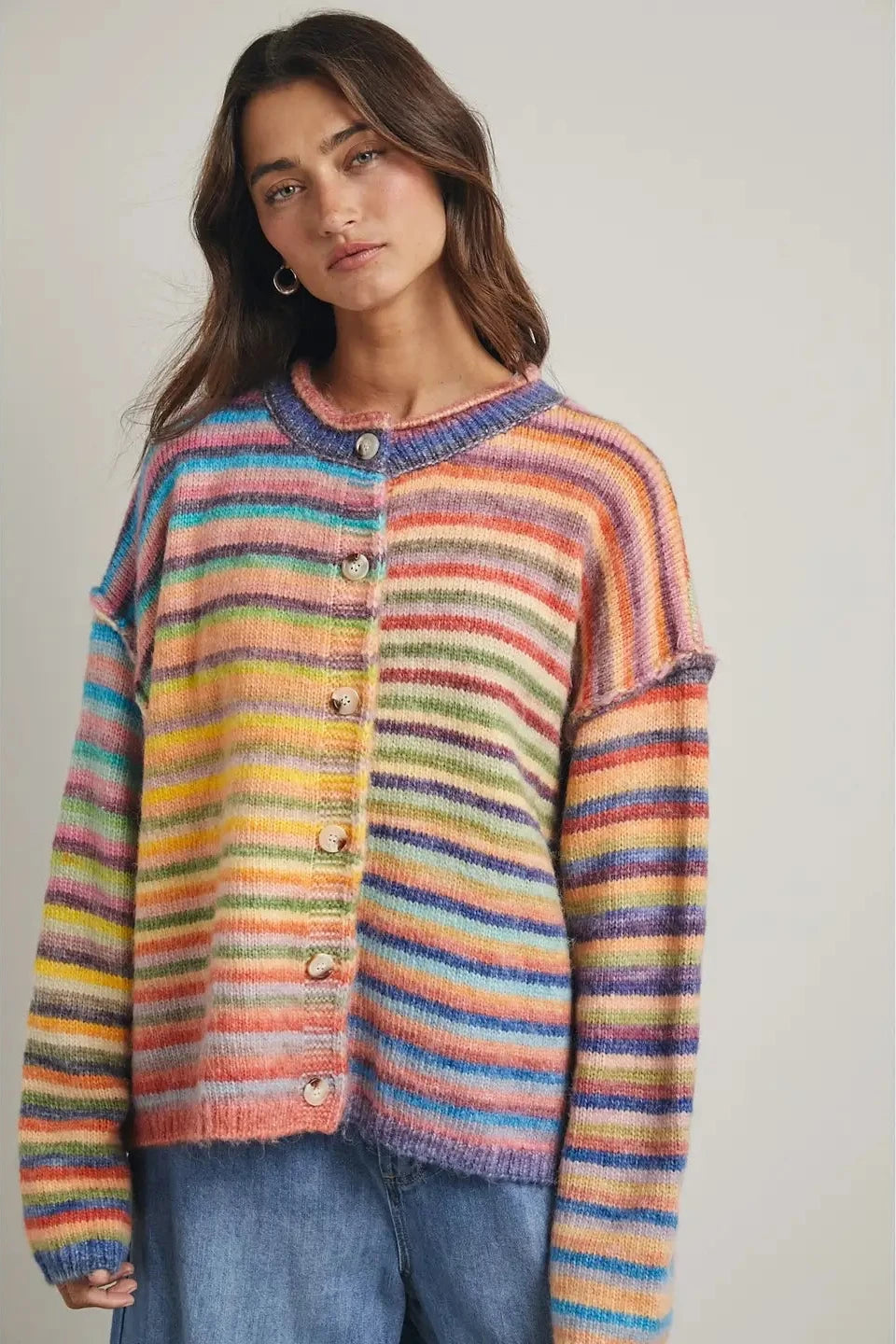 Woman wearing a colorful striped sweater against a plain background
