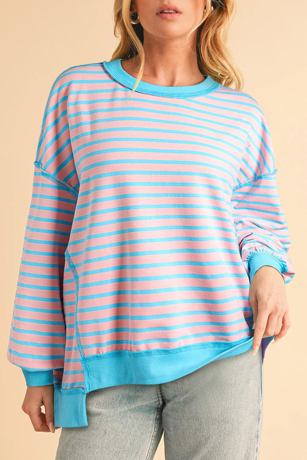Person wearing a pink and blue striped sweater against a beige background