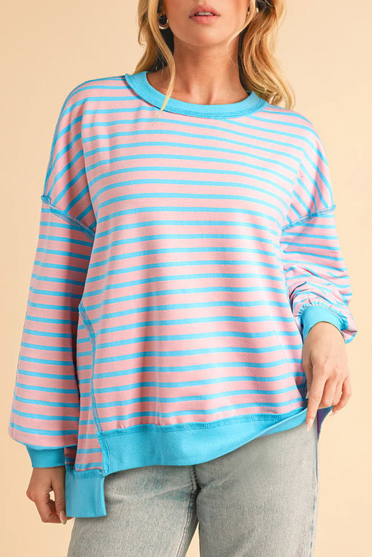 Person wearing a pink and blue striped sweater against a beige background