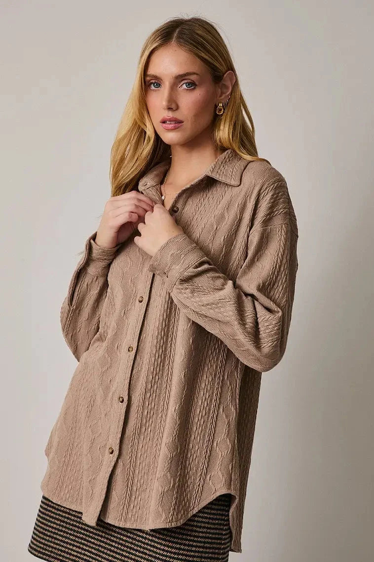 Woman wearing a beige textured shirt against a plain background