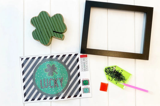 Decorative items including a shamrock, a framed picture, a card with 'Lucky' text, and a lollipop on a white surface.