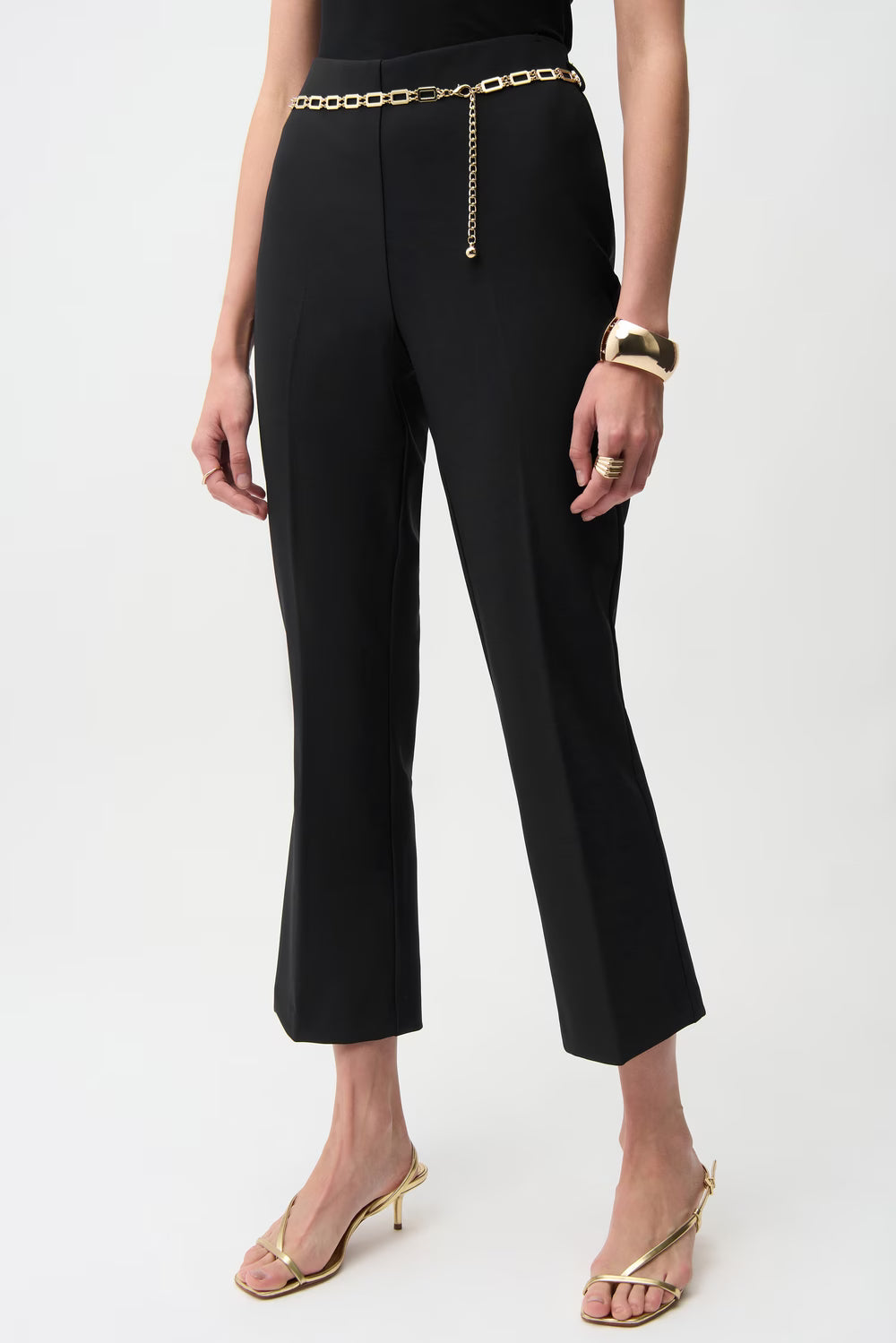 Person wearing black pants with a gold chain belt on a white background