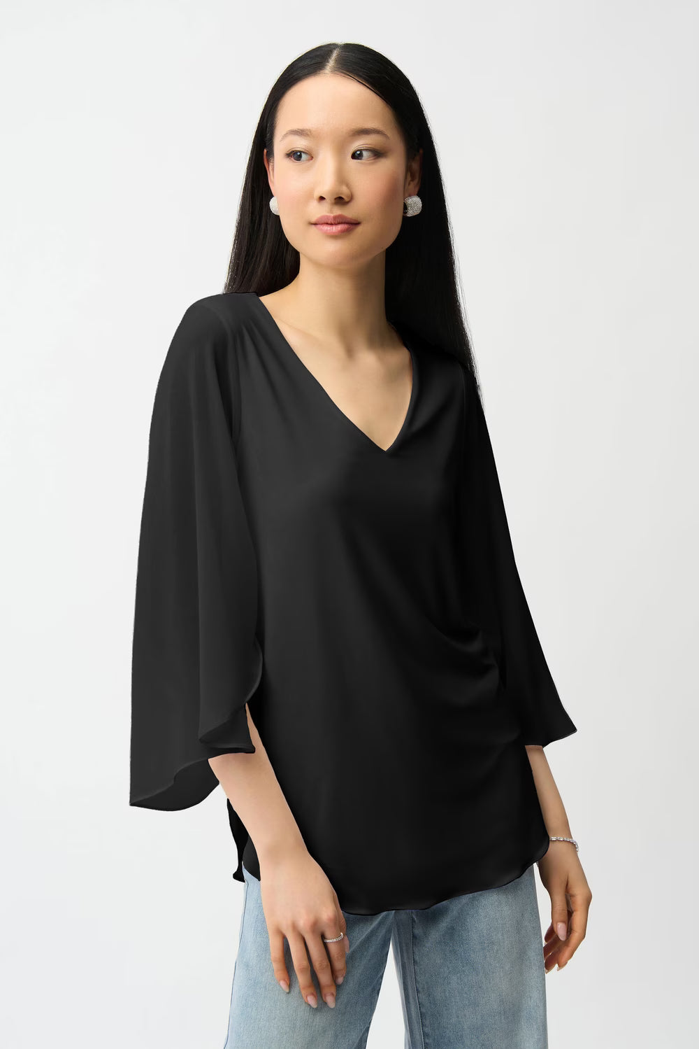 Woman wearing a black blouse and light blue jeans on a white background