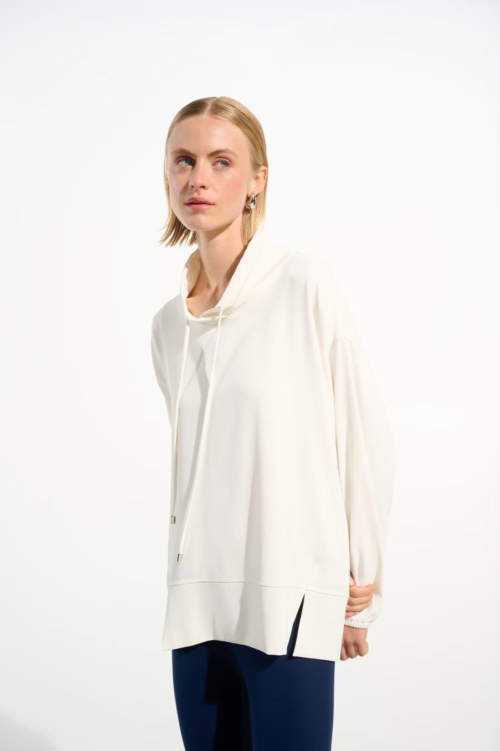 Woman wearing a white long-sleeve top and blue pants on a white background