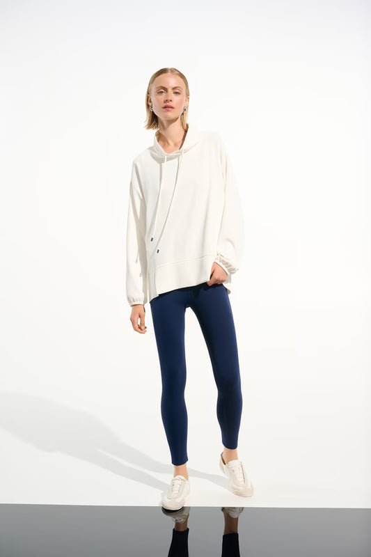 Woman wearing a white hoodie and blue leggings on a white background