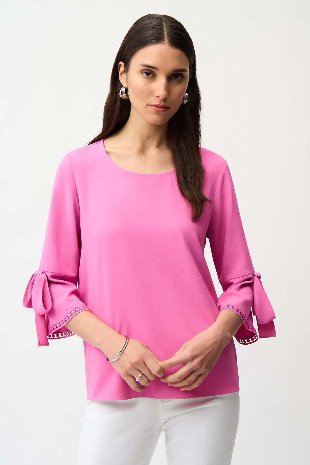 Woman wearing a pink blouse with bow cuffs on a white background