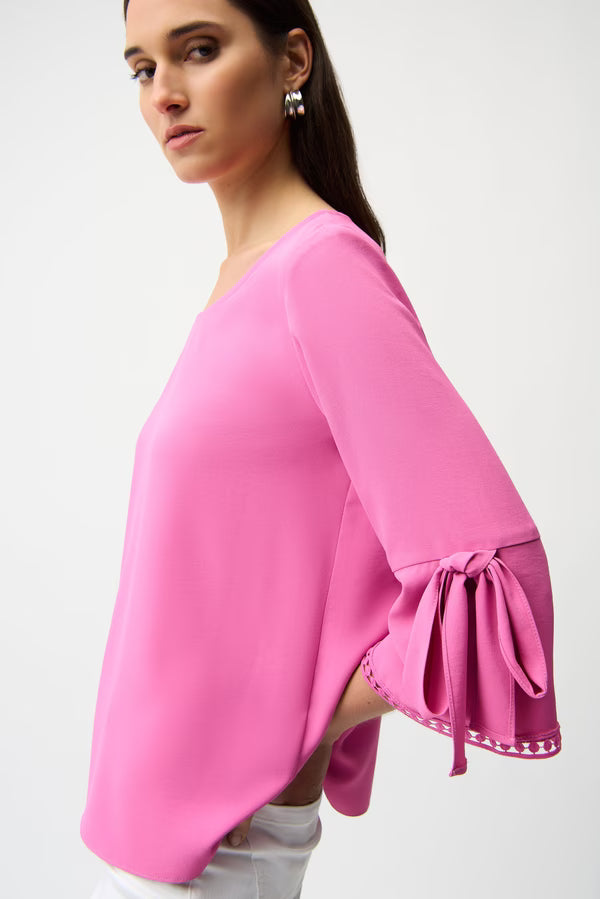 Woman wearing a pink blouse with tied sleeves on a white background