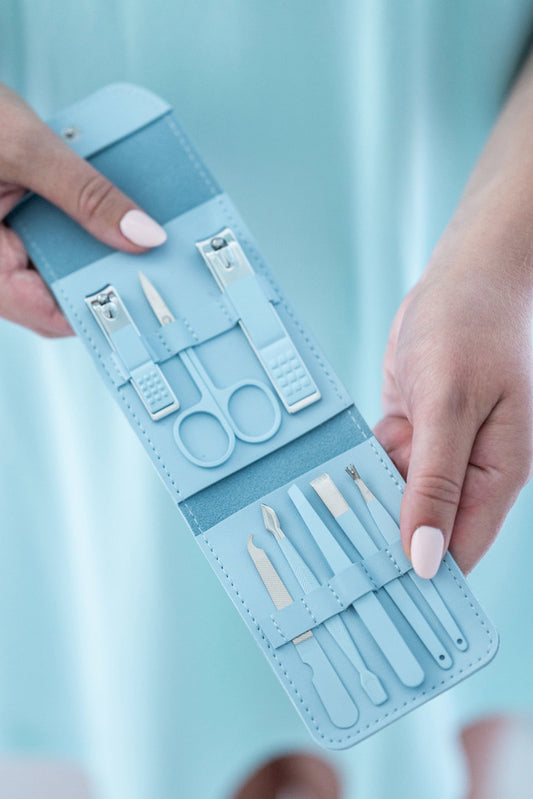 Blue manicure set with tools held by a person against a light blue background