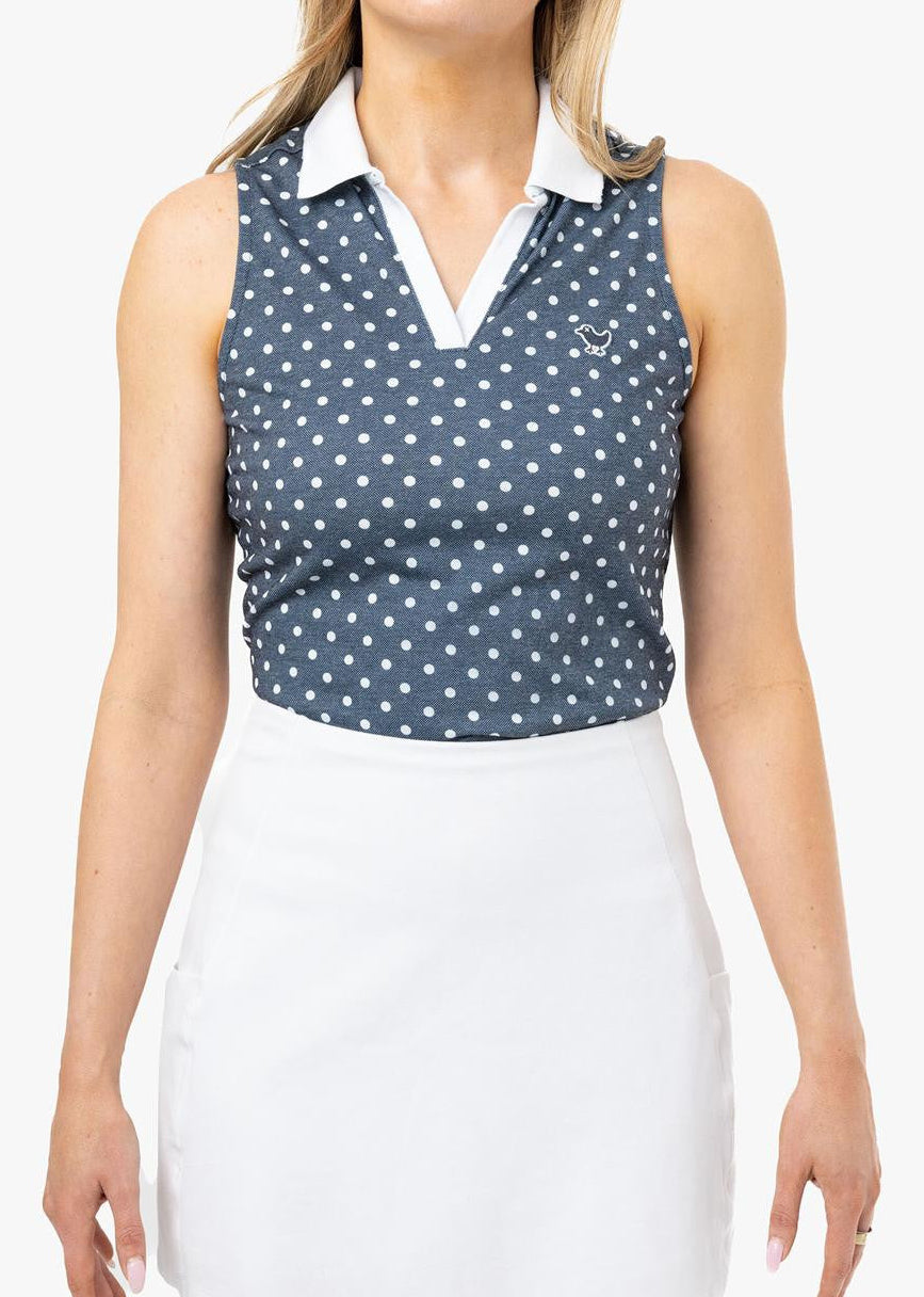 Woman wearing a sleeveless polka dot top and white skirt on a white background